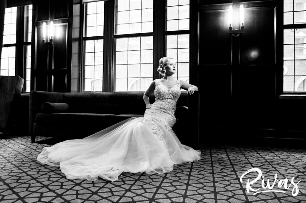 Art Deco Inspired Wedding in Kansas City | A dramatic black and white portrait of a bride in an art-deco inspired wedding dress sitting on the edge of a couch at Kansas City's Hotel Phillips on her wedding day. 