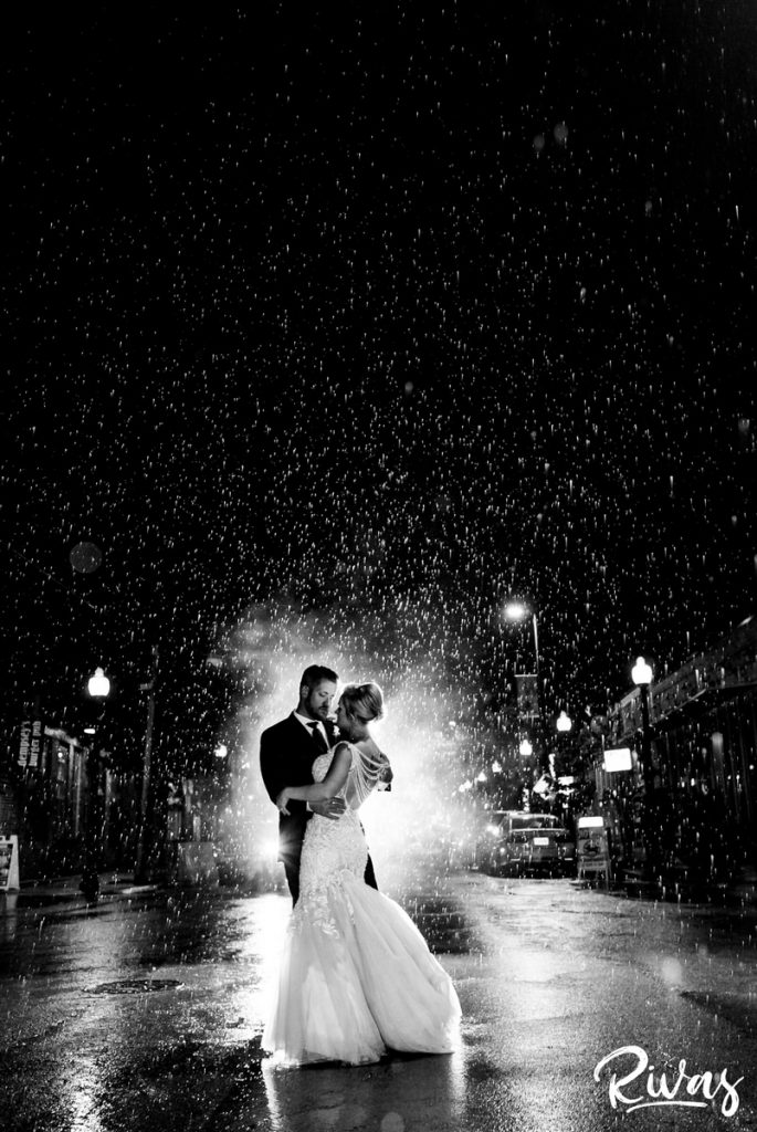 Art Deco Inspired Wedding in Kansas City-A candid image of a bride and groom dancing in the street as it rains around them after their wedding reception at Californos in Kansas City. 