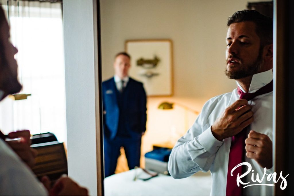 Art Deco Inspired Wedding in Kansas City | A candid picture taken in a mirror of a groom straightening his tie on the morning of his wedding. 