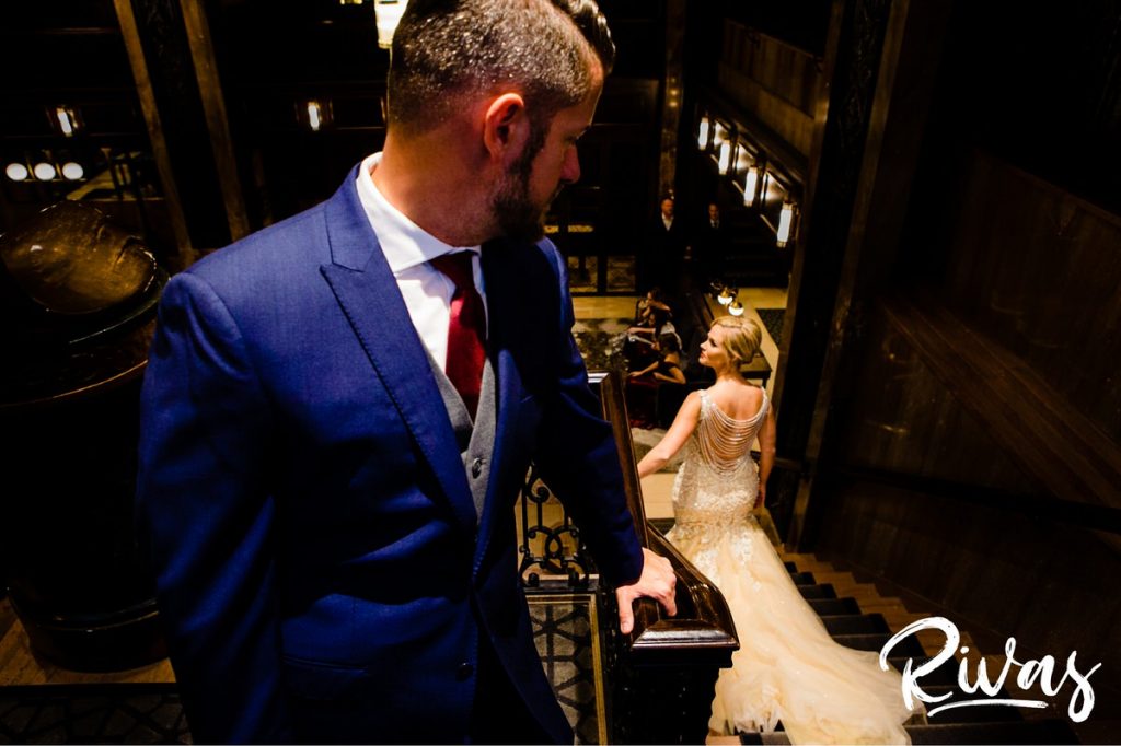 Art Deco Inspired Wedding in Kansas City | A candid moment of a groom looking back over his shoulder as his bride walks down the stairs of Hotel Phillips in downtown Kansas City. 