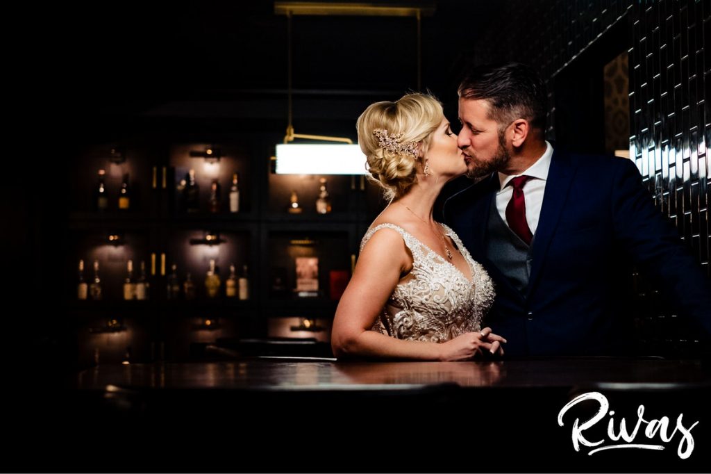 Art Deco Inspired Wedding in Kansas City | A candid picture of a bride and groom leaning against a bar table in the Hotel Phillips Speakeasy on their wedding day. 