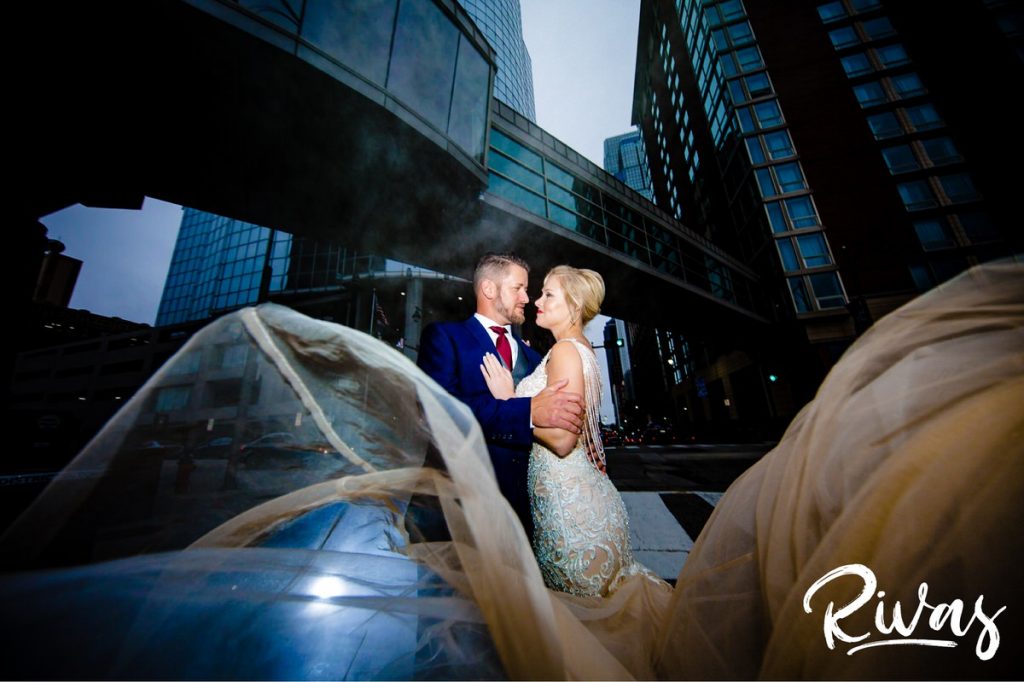 Art Deco Inspired Wedding in Kansas City | A center focused portrait of a bride and groom standing in the middle of a downtown Kansas City street as the bride's gown blows in the wind on their wedding day. 