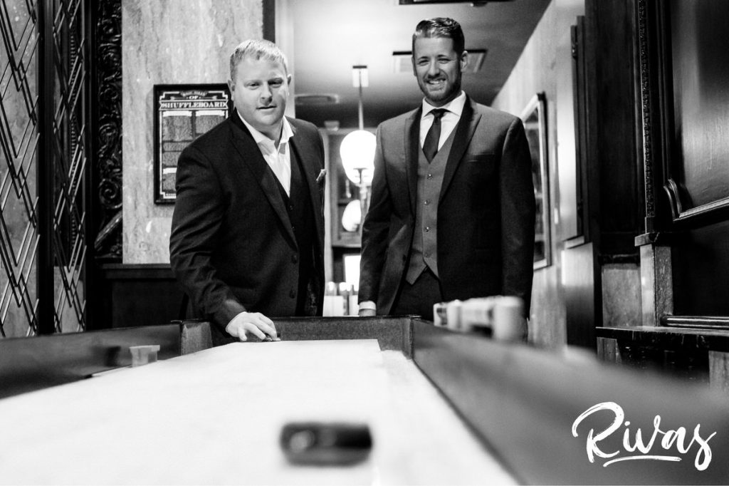 Art Deco Inspired Wedding in Kansas City | A candid black and white picture of a group of men playing shuffleboard in the lobby of Kansas City's Hotel Phillips. 
