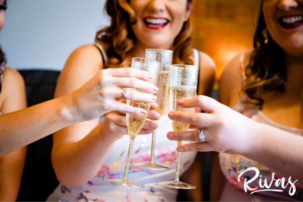 Downtown KC Library Wedding | A candid picture of a bride and her bridesmaids toasting with their champagne flutes on the morning of her wedding. 