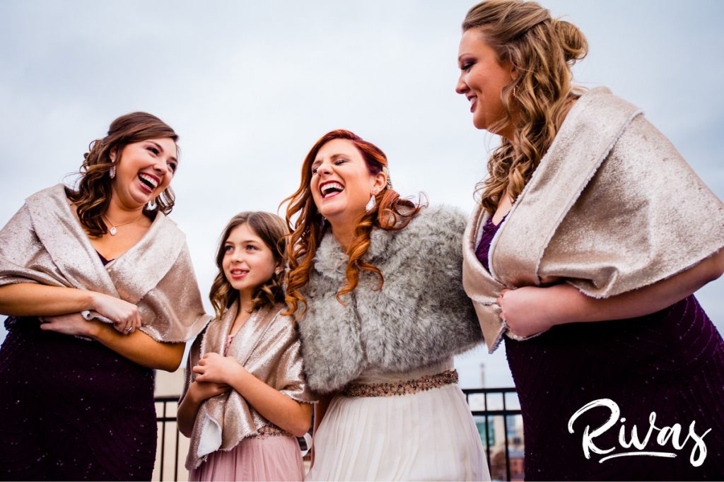Downtown KC Library Wedding | A close-up picture of a bride laughing hysterically with her bridesmaids and flower girl on the morning of her winter wedding in Kansas City. 