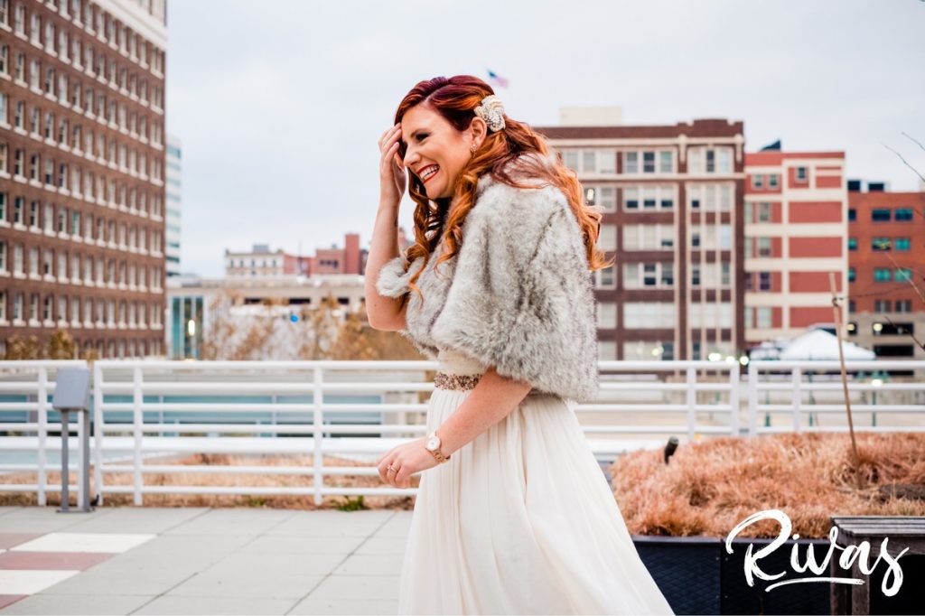 Downtown KC Library Wedding | a candid picture of a bride in a fur shawl walking towards her groom for their first look on the morning of their wedding day.