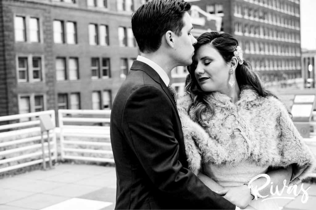 Downtown KC Library Wedding | An intimate black and white picture of a groom kissing his bride on the forehead just after their first look.