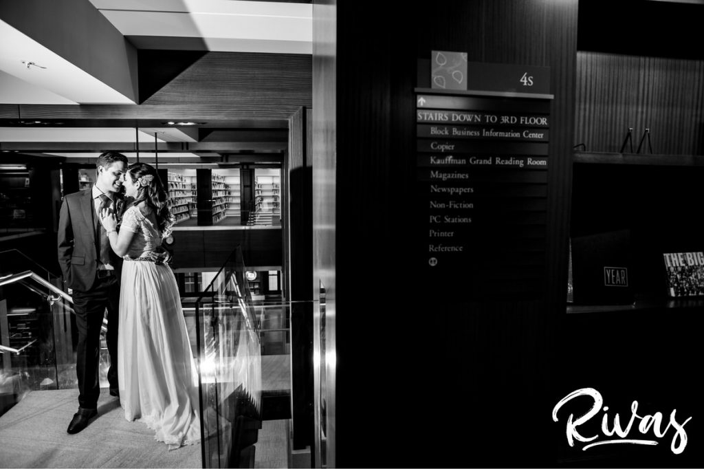 Downtown KC Library Wedding | A candid, black and white picture of a bride and groom sharing an embrace on their wedding day in the downtown Kansas City public library.