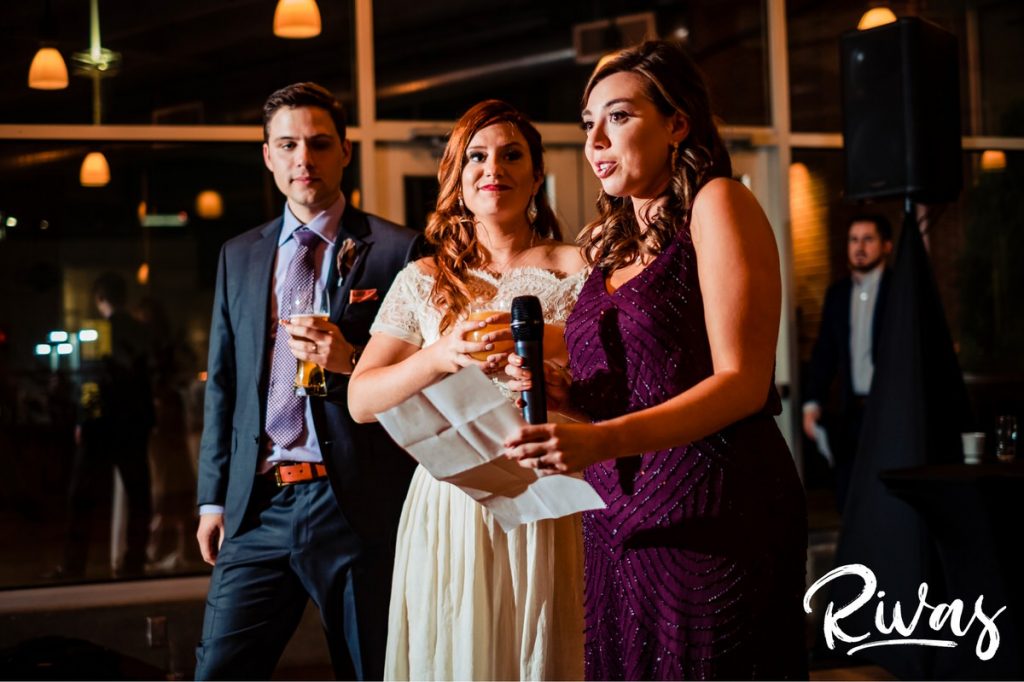 Downtown KC Library Wedding - Rivas Photography | A picture of a nervous bridesmaid dressed in a purple sequined gown giving a toast to a bride and groom during their wedding reception at Boulevard Brewing Company. 