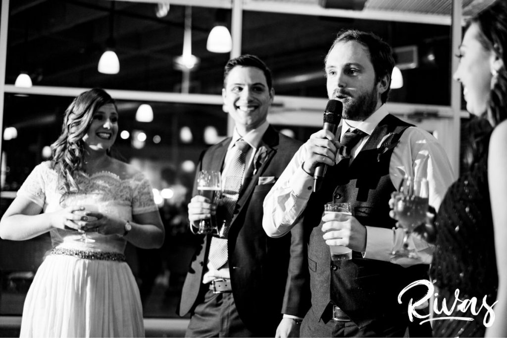 Downtown KC Library Wedding - Rivas Photograph | A black and white candid image of a groomsman toasting his best friend and bride during their wedding reception at Kansas City's Boulevard Brewing Company. 