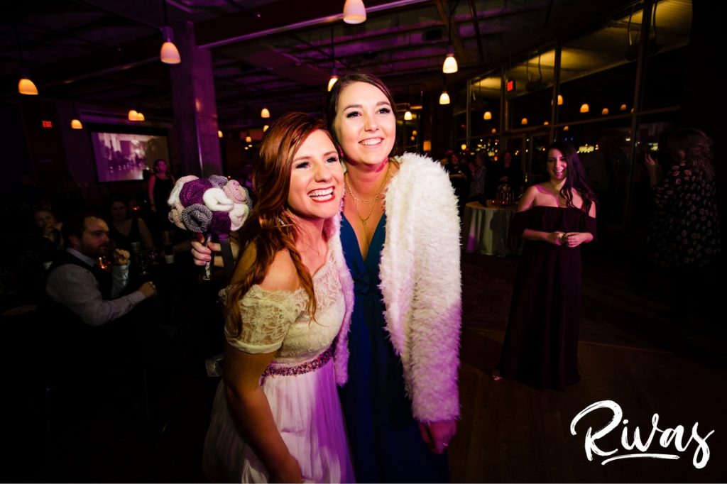 Downtown KC Library Wedding - Rivas Photography | A candid picture of a bride and the woman who caught her tossed bouquet at her Boulevard Brewing Company wedding reception. 