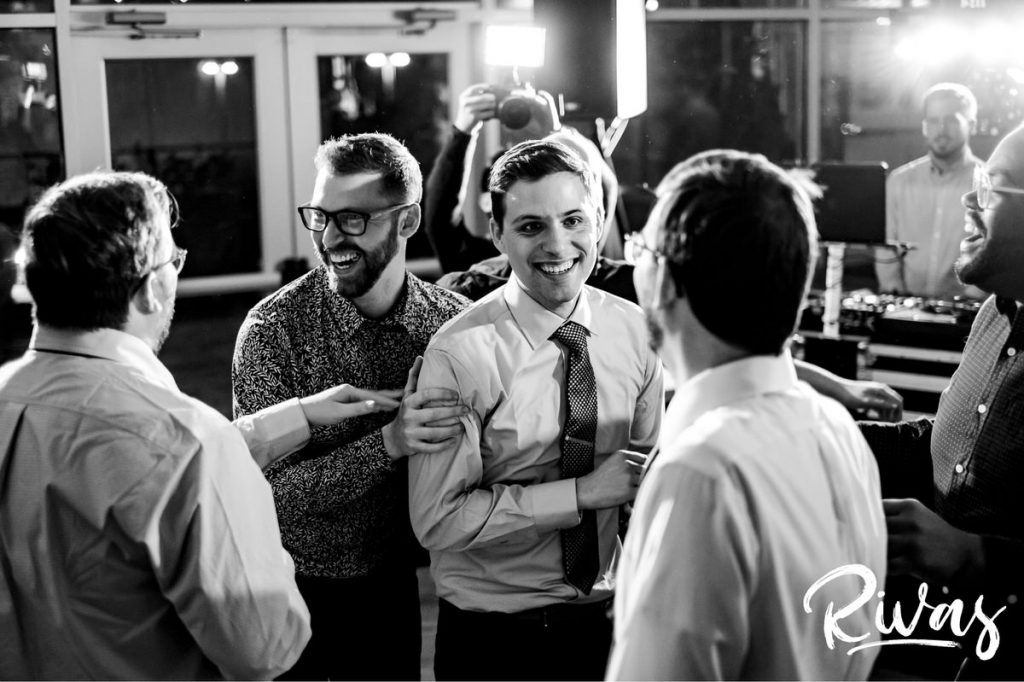 Downtown KC Library Wedding - Rivas Photography | A candid black and white picture of a groom surrounded by his dancing friends during his Boulevard Brewing Company wedding reception in Kansas City. 