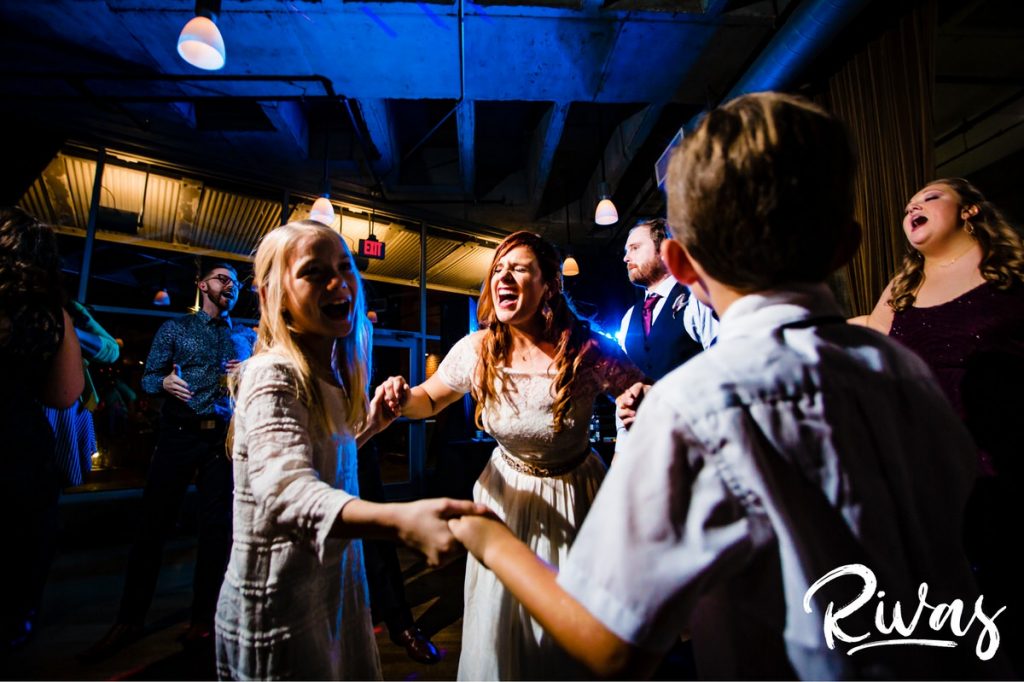 Downtown KC Library Wedding - Rivas Photography | A candid picture of a bride dancing with her young cousins during her wedding reception at Boulevard Brewing. 