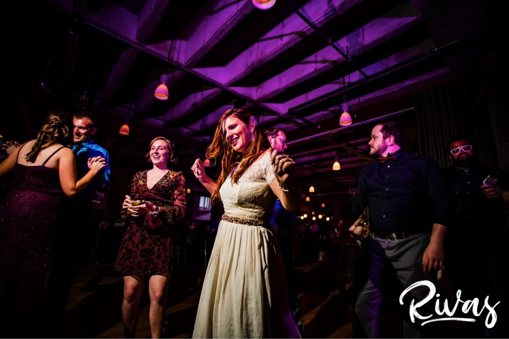 Downtown KC Library Wedding - Rivas Photography | A vibrant picture of a bride dancing in the middle of the dance floor surrounded by friends and family during her wedding reception at Boulevard Brewing Company. 