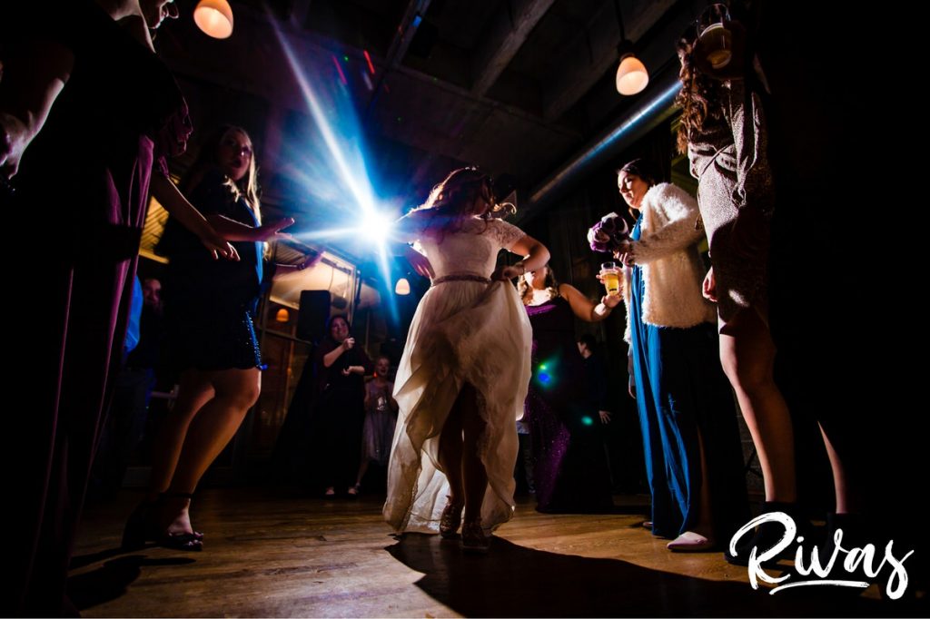 Downtown KC Library Wedding - Rivas Photography | A vibrant picture of a bride dancing in the middle of the dance floor surrounded by friends and family during her wedding reception at Boulevard Brewing Company. 