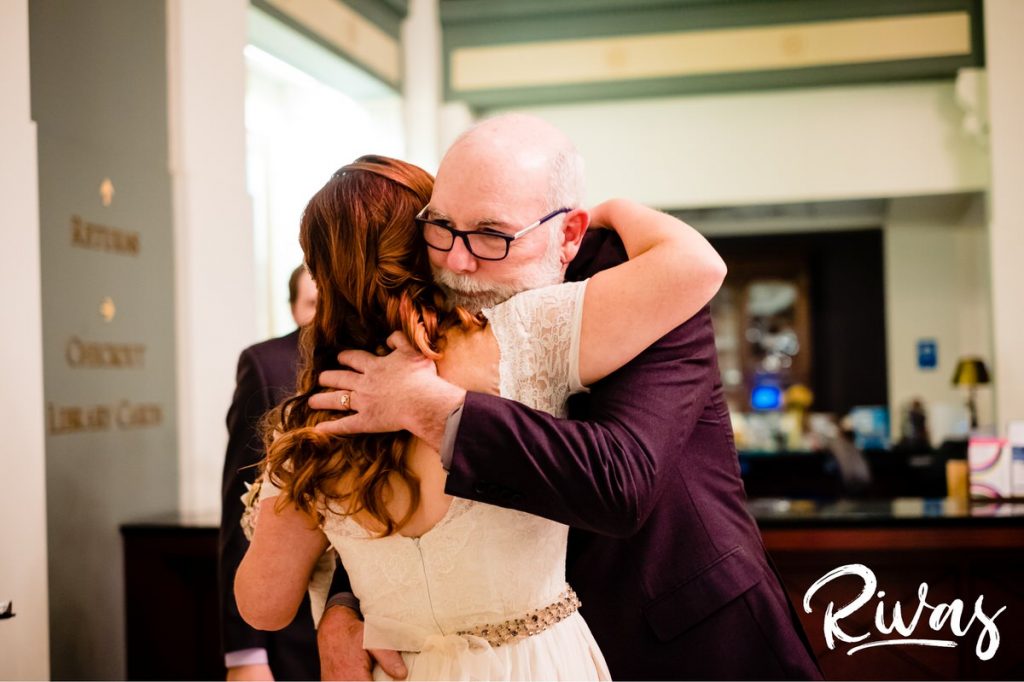 Downtown KC Library Wedding | A candid picture taken during a wedding ceremony of a bride's dad hugging her as he gives her away.