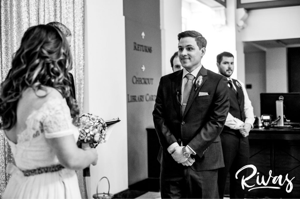 Downtown KC Library Wedding | A candid black and white picture taken during a wedding ceremony of a groom lovingly looking at his bride.