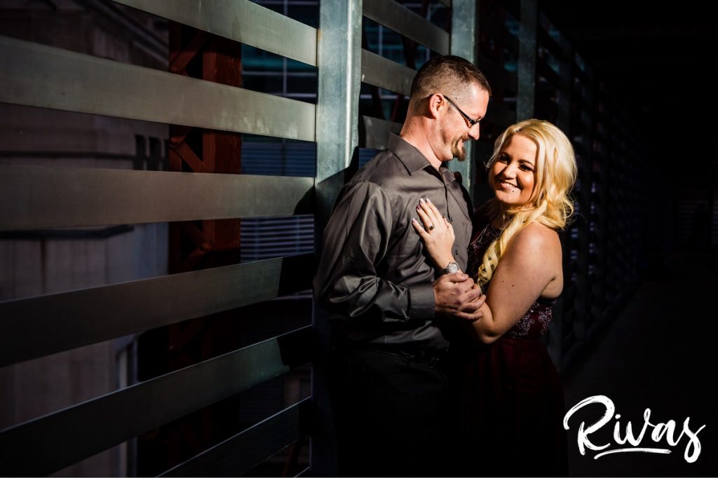 Nighttime Car Engagement Session | A candid picture of an engaged couple dressed up, laughing and sharing an embrace during their nighttime engagement session in Kansas City.