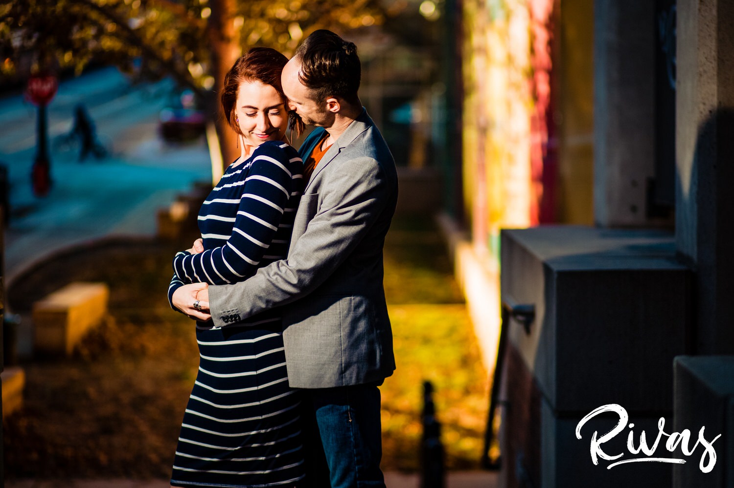 A vibrant picture of an engaged couple sharing an embrace in front of the downtown Kansas City library parking garage during their engagement session