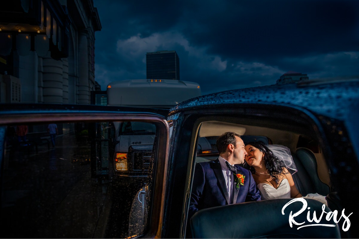 Stylish Scarritt Building Wedding | Kansas City Wedding Photographer | Rivas | A photo of a bride and groom sharing a kiss in the back of a classic car on their stormy wedding day in Kansas City.