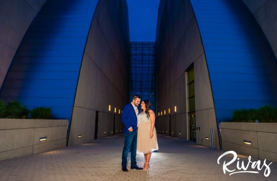 Summer Engagement Session Sneak Peek | Kansas City Wedding Photographers | A portrait of an engaged couple sharing an embrace while standing in front of Kansas City's Kauffman Center for the Performing Arts during their evening engagement session.