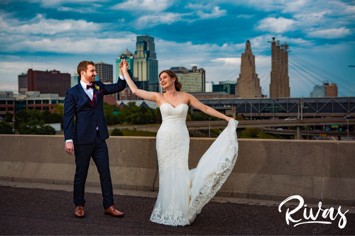 Strawberry Hil Summer Wedding Sneak Peek | A candid image of a bride and groom dancing in front of the Kansas City skyline taken from the Summit Street Bridge.