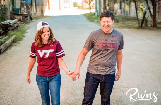 West Bottoms Engagement Pictures | a picture of a couple dressed in Virginia Tech gear holding hands and laughing together in Kansas City's West Bottoms neighborhood.