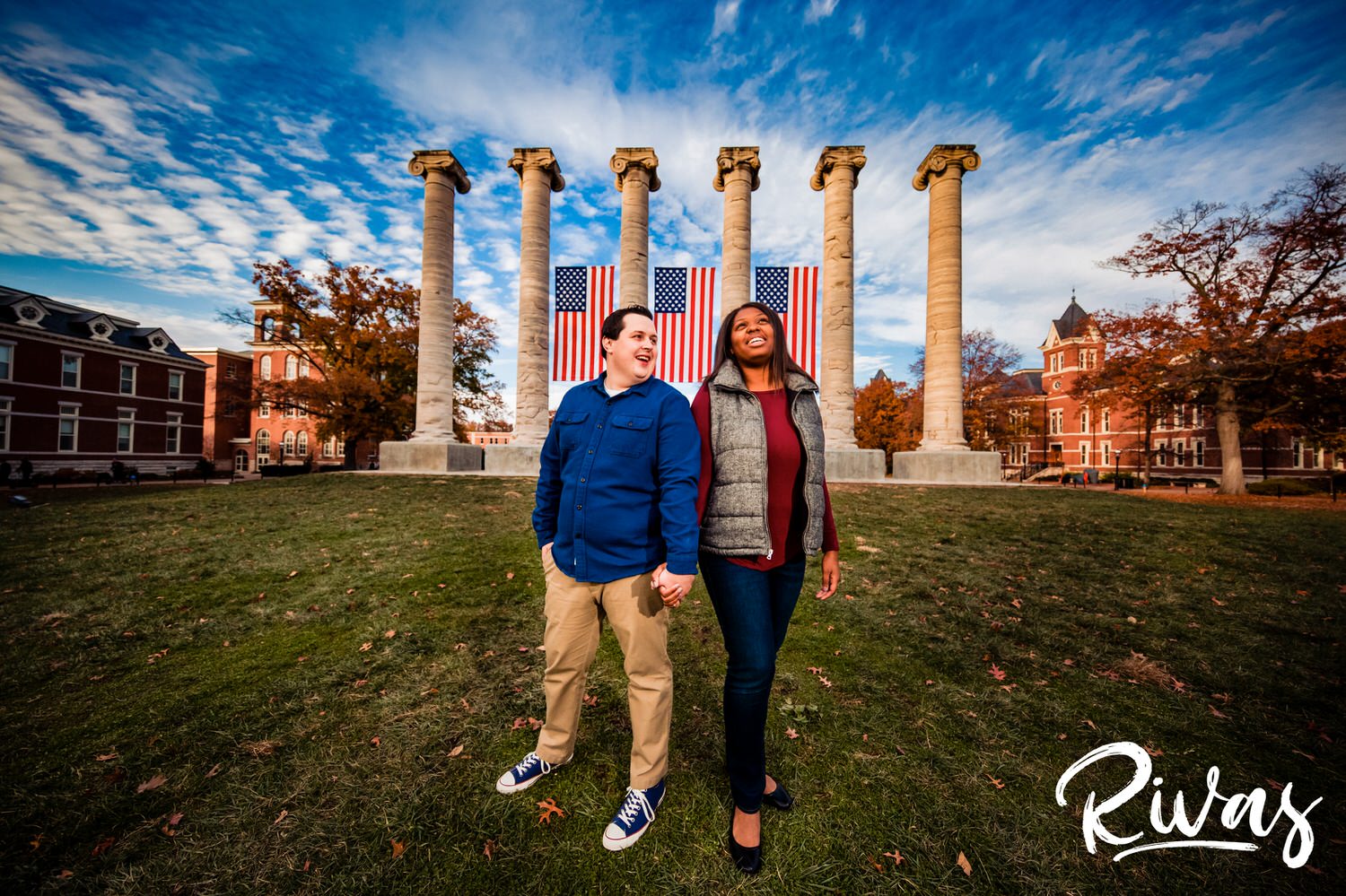 Fall MU Engagement Session | A wide, colorful picture of an engaged couple holding hands while standing in front of the Mizzou columns during their engagement session.