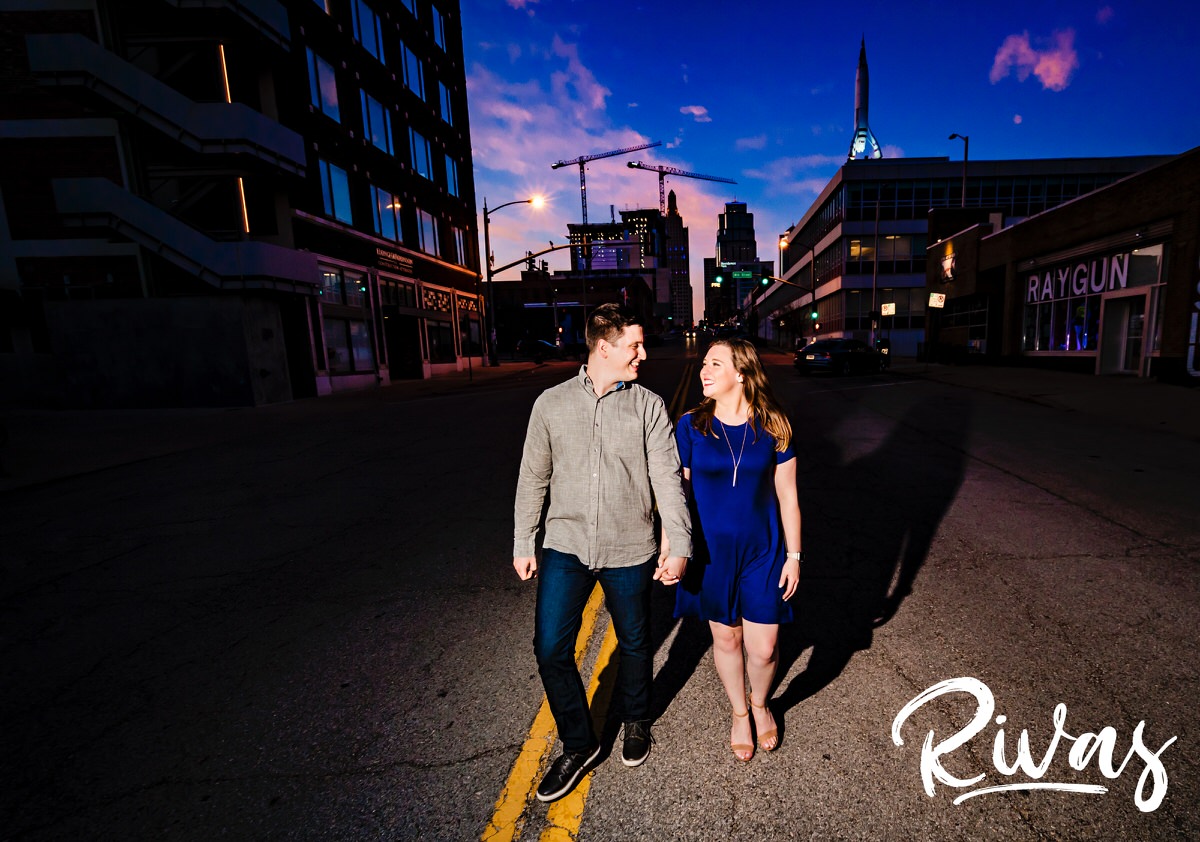 A vibrant, colorful picture of an engaged couple holding hands as they walk through Kansas City's Crossroads District during their spring engagement session. 