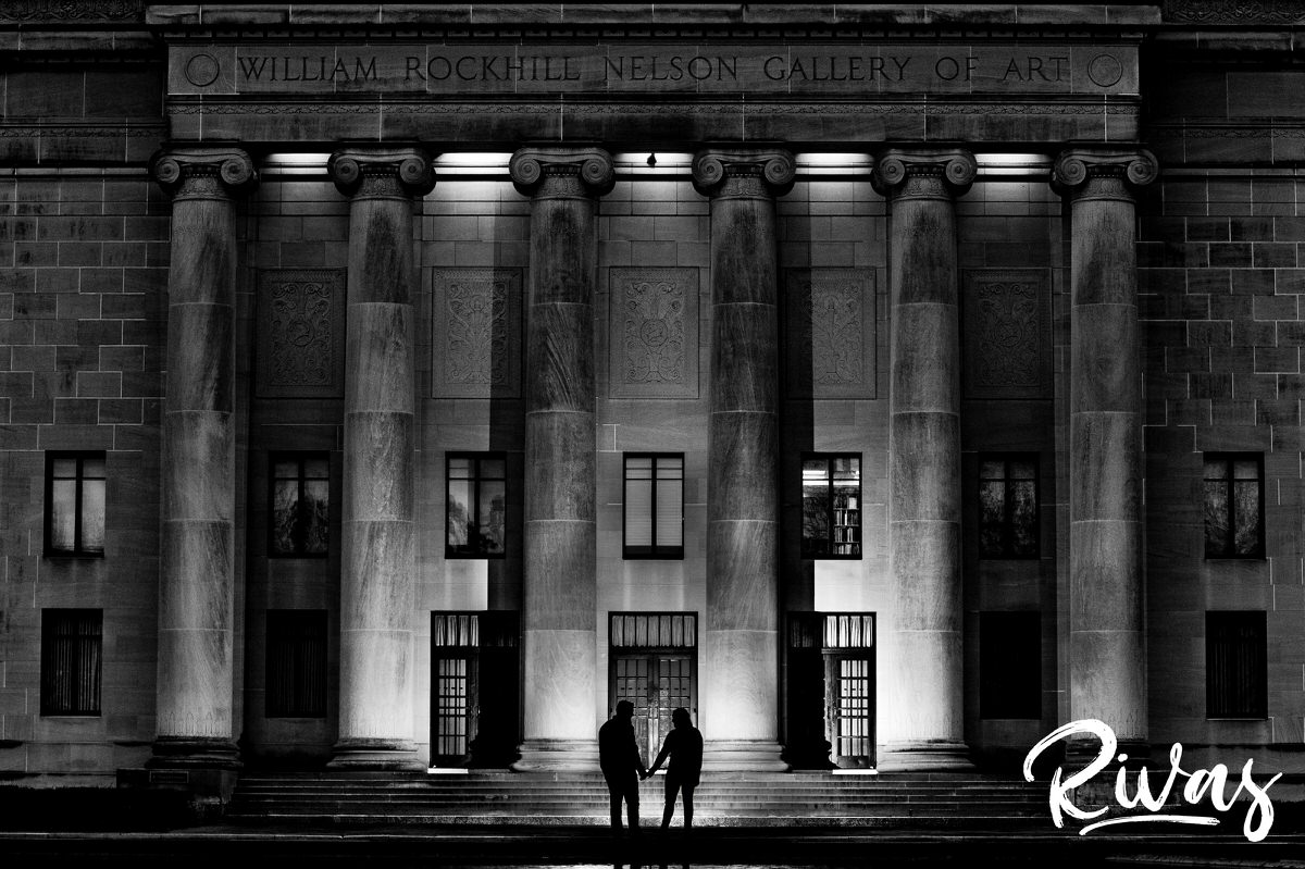 A black and white, dramatic picture of a couple silhouetted against the columns of the Nelson Atkins Museum of Art in Kansas City. 