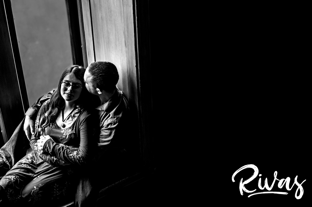 A candid black and white picture of an engaged couple sitting in a window sill during their morning engagement session at Union Station. 