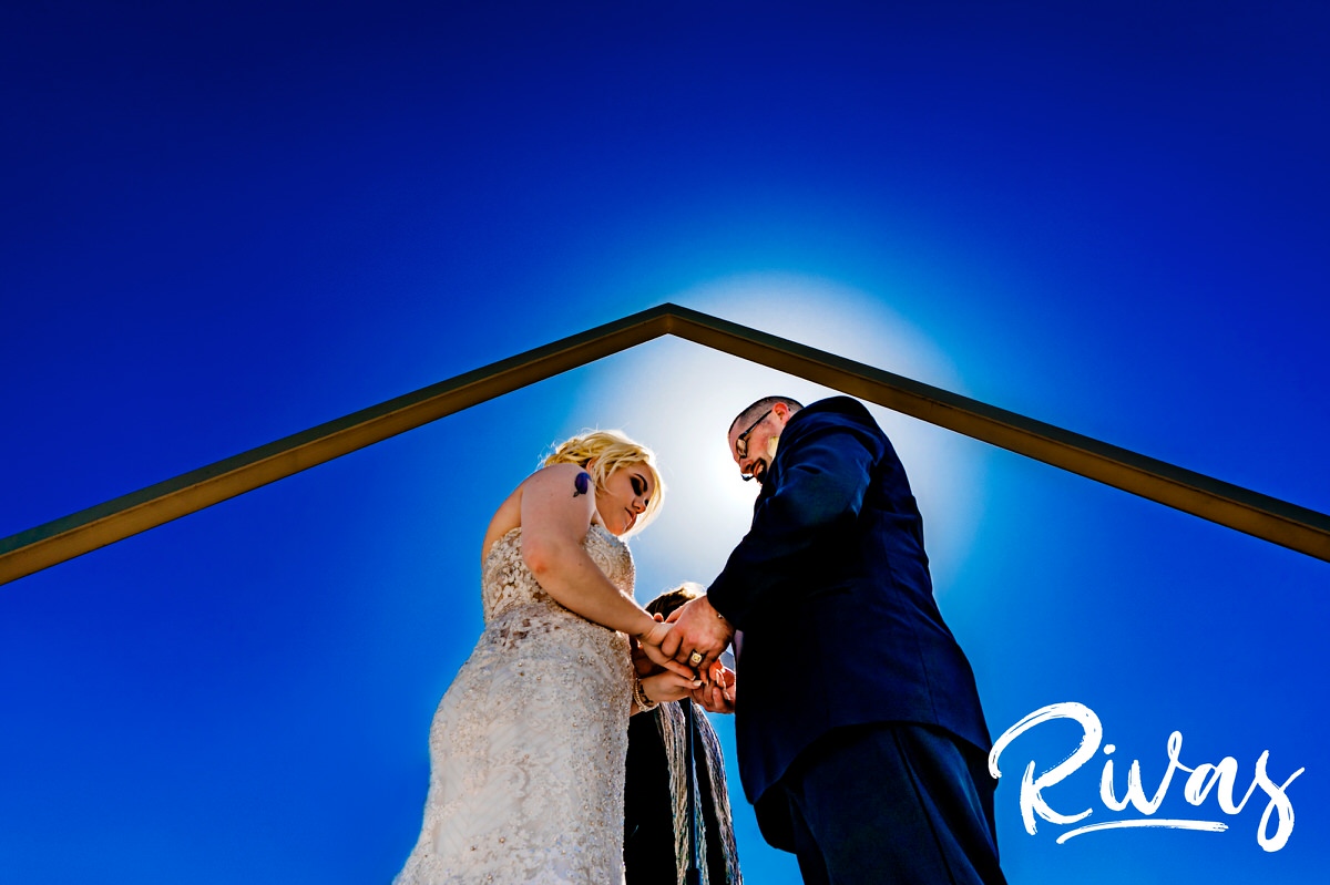 A vibrant, candid picture of a bride and groom clasping their hands together in prayer during their sunny wedding ceremony at The Pavilion Event Space. 