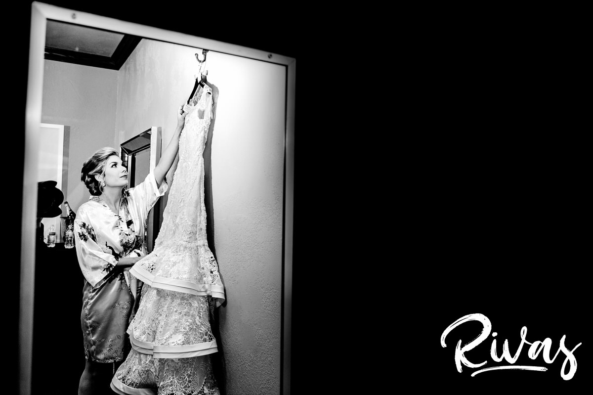 A candid, black and white picture of a bride reaching for her wedding gown on the morning of her winter wedding at The Stanley in downtown Lee's Summit. 