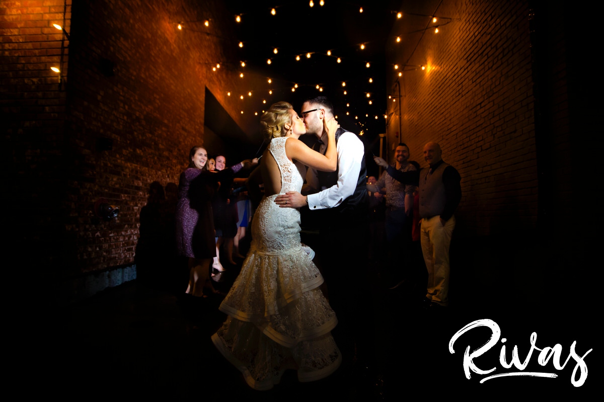A candid picture of a bride and groom sharing a kiss at the end of their sparkler ext on the evening of their winter wedding at The Stanley in Lee's Summit. 
