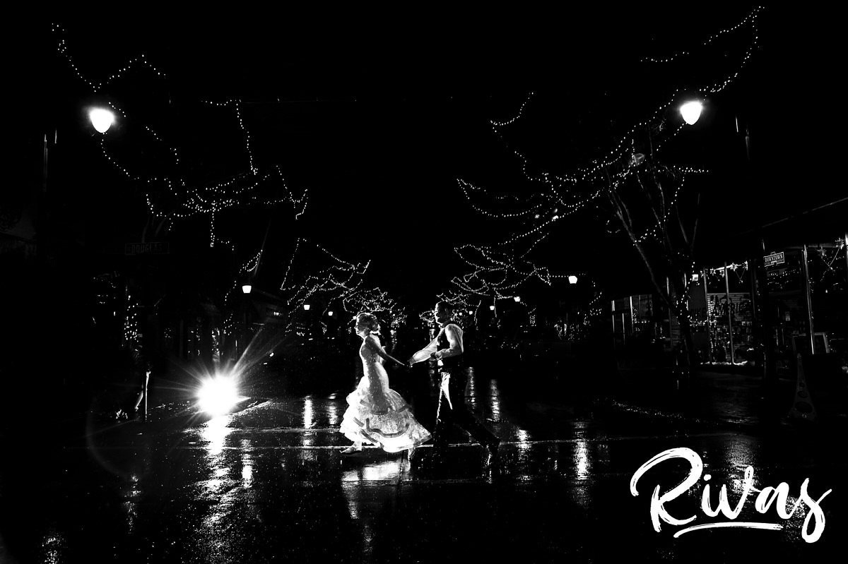 A candid picture of a bride and groom running through the rain across the street at the end of their winter wedding day in downtown LEe's Summit. 