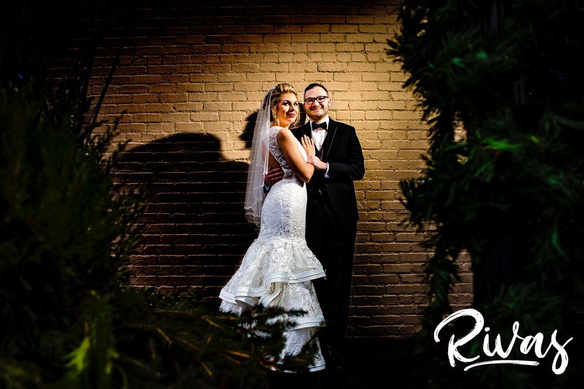 A portrait of a bride and groom standing up against a brick wall on their winter wedding day in downtown Lee's Summit's The Stanley Event Space. 