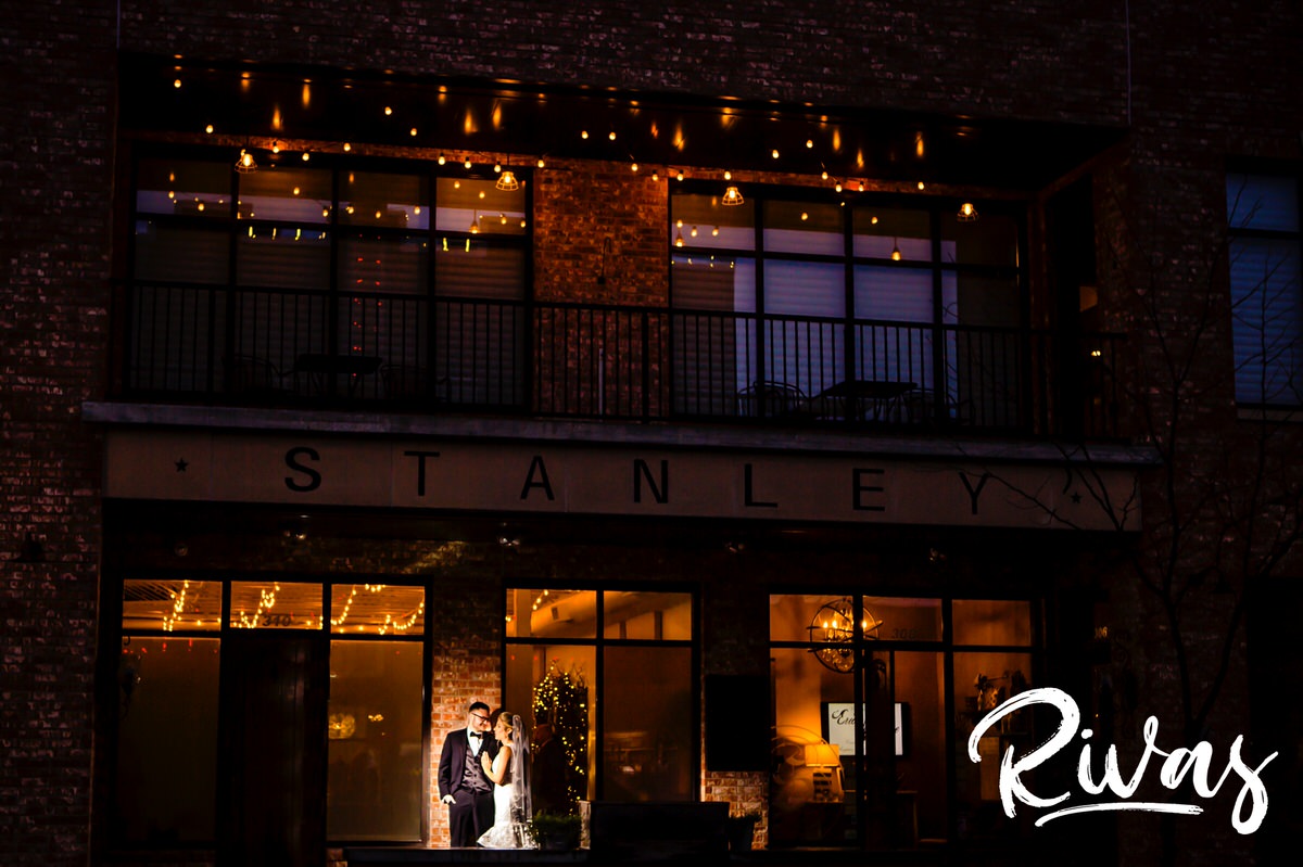 A wide picture of a bride and groom standing outside The Stanley Event Space in downtown Lee's Summit on their wedding day. 
