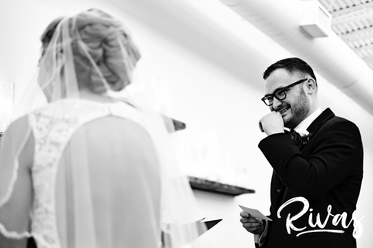 A candid black and white picture of a groom laughing as he says his wedding vows to his bride during their winter wedding at The Stanley in Lee's Summit. 