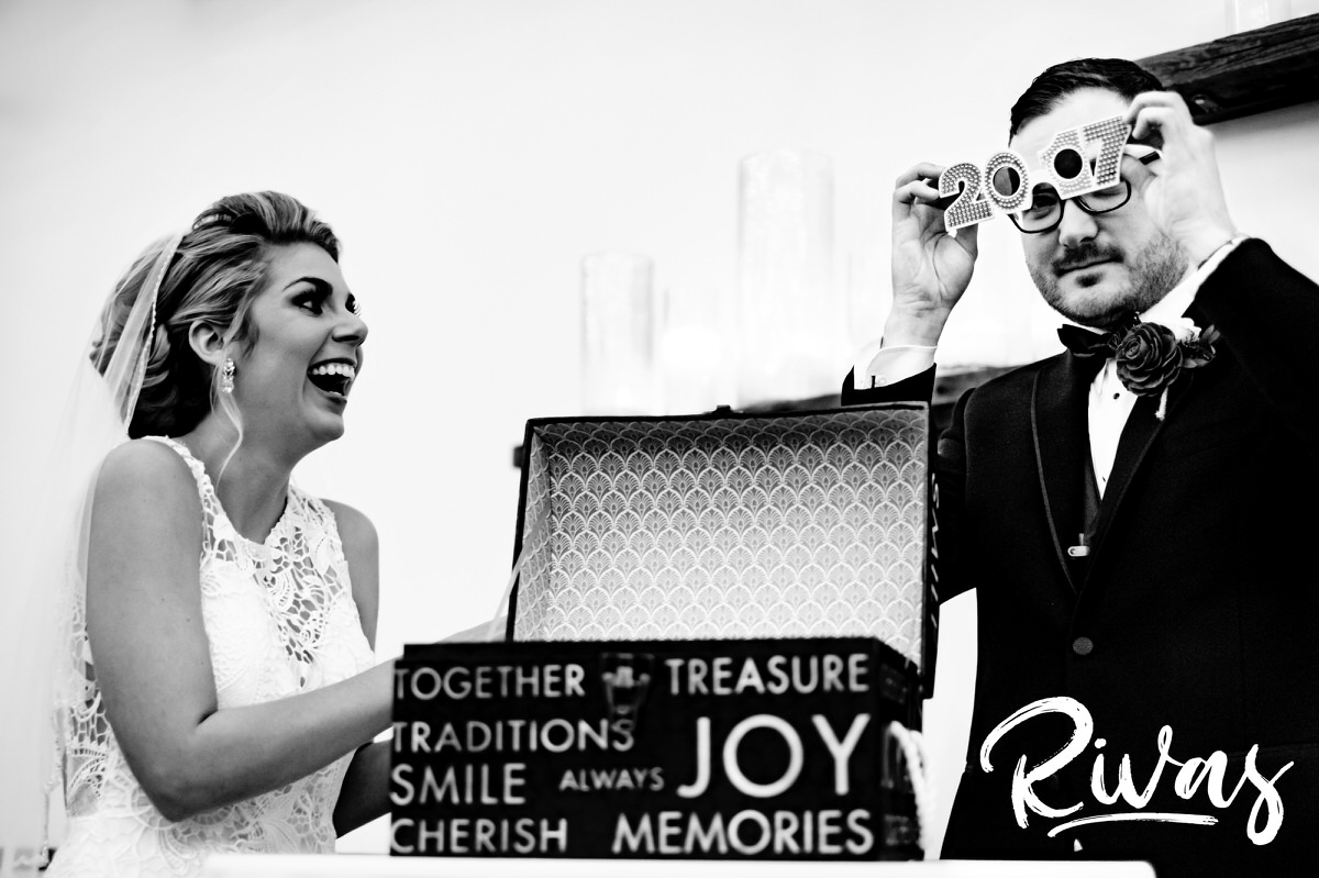 A candid black and white picture of a bride and groom putting momentos into a time capsule box during their winter wedding ceremony at The Stanley in downtown Lee's Summit. 
