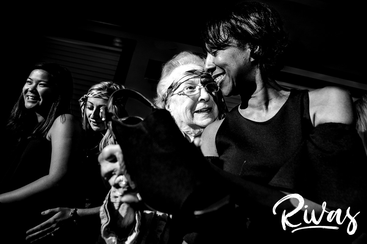 A candid black and white picture of a woman sitting on the groom's grandma's lap during a reception game at a winter wedding at The Stanley in downtown Lee's Summit. 