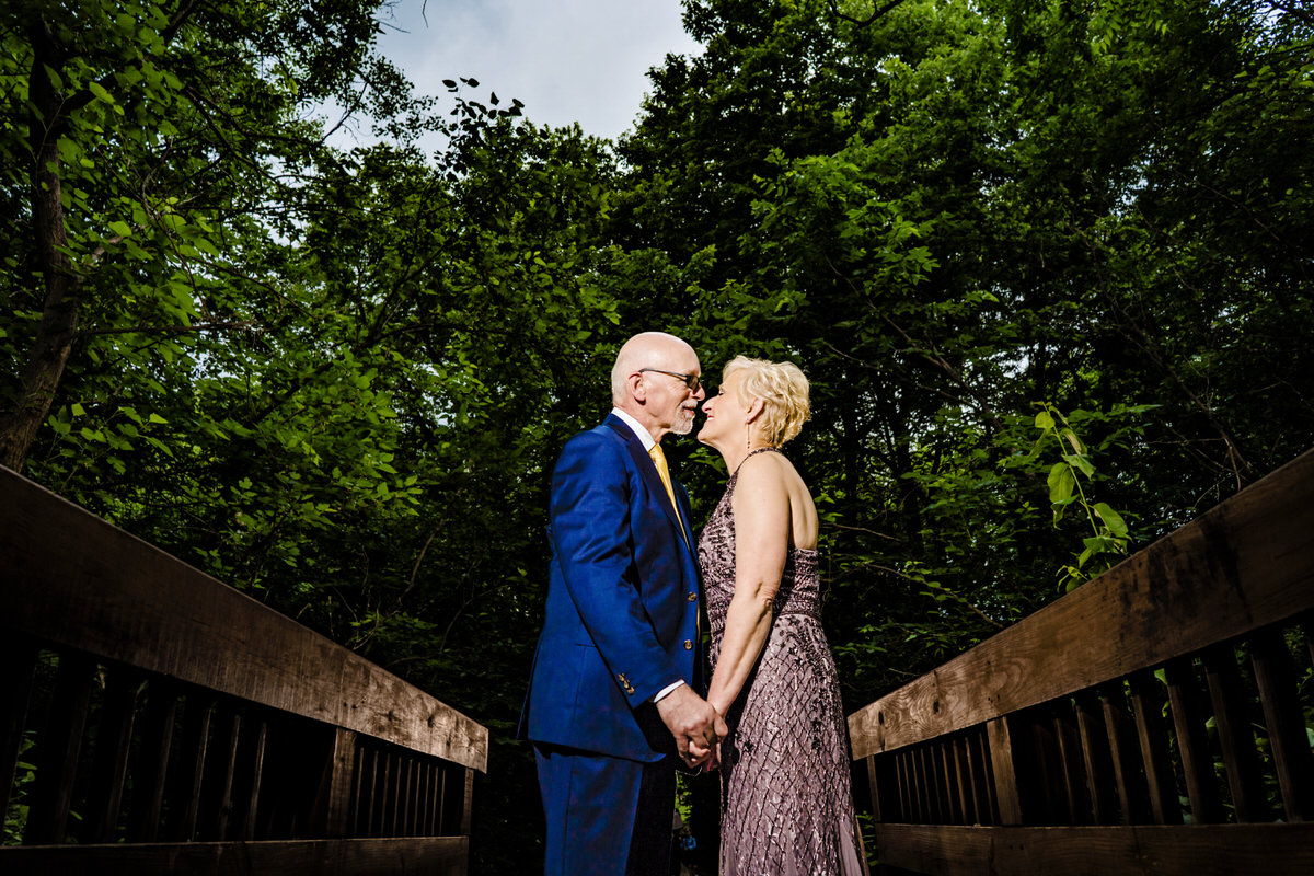 A candid picture of a bride and groom holding hands and standing on a bridge during their intimate wedding day at Omaha's OPPD Arboretum.