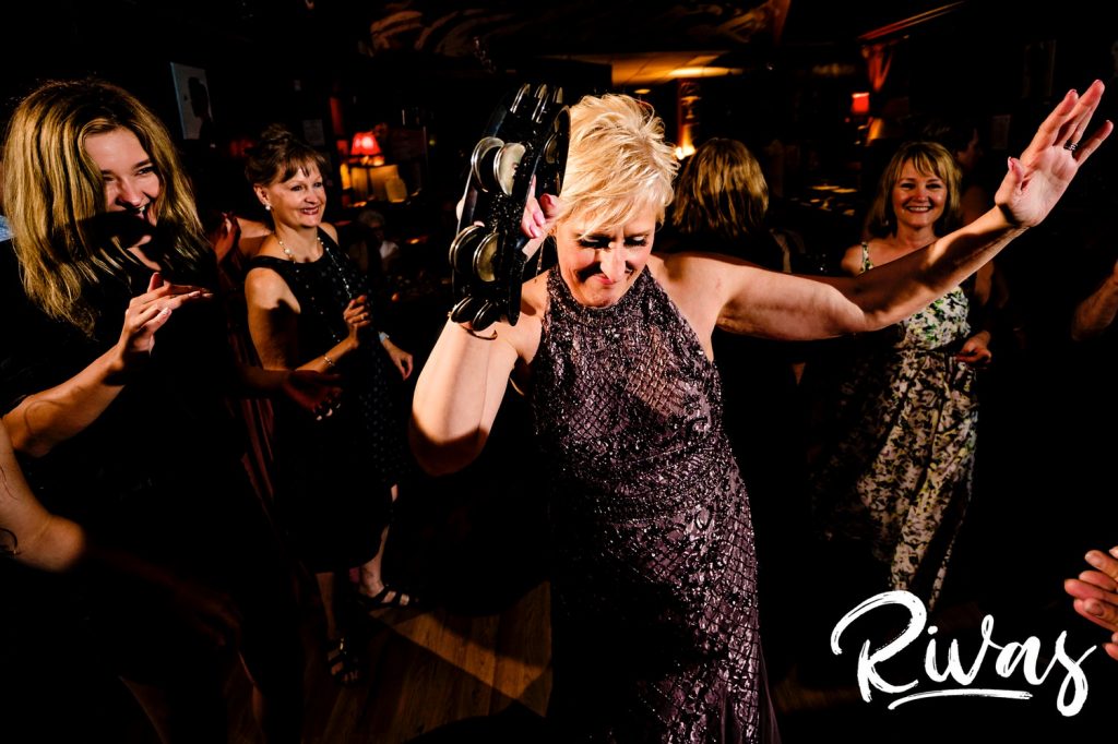 A fun, colorful picture of a bride playing the tambourine as she dances on the dance floor during her wedding reception at The B Side of the Benson Theater in Omaha. 