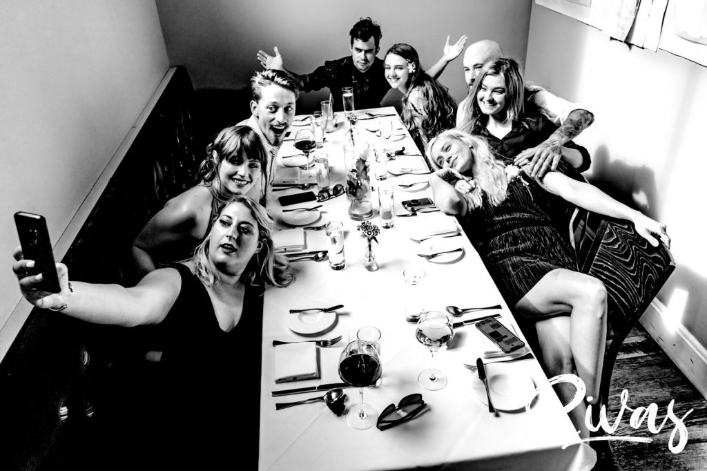 A candid, black and white picture of a bride and groom's grown children celebrating their marriage at The Grey Plume for dinner after their Omaha wedding. 