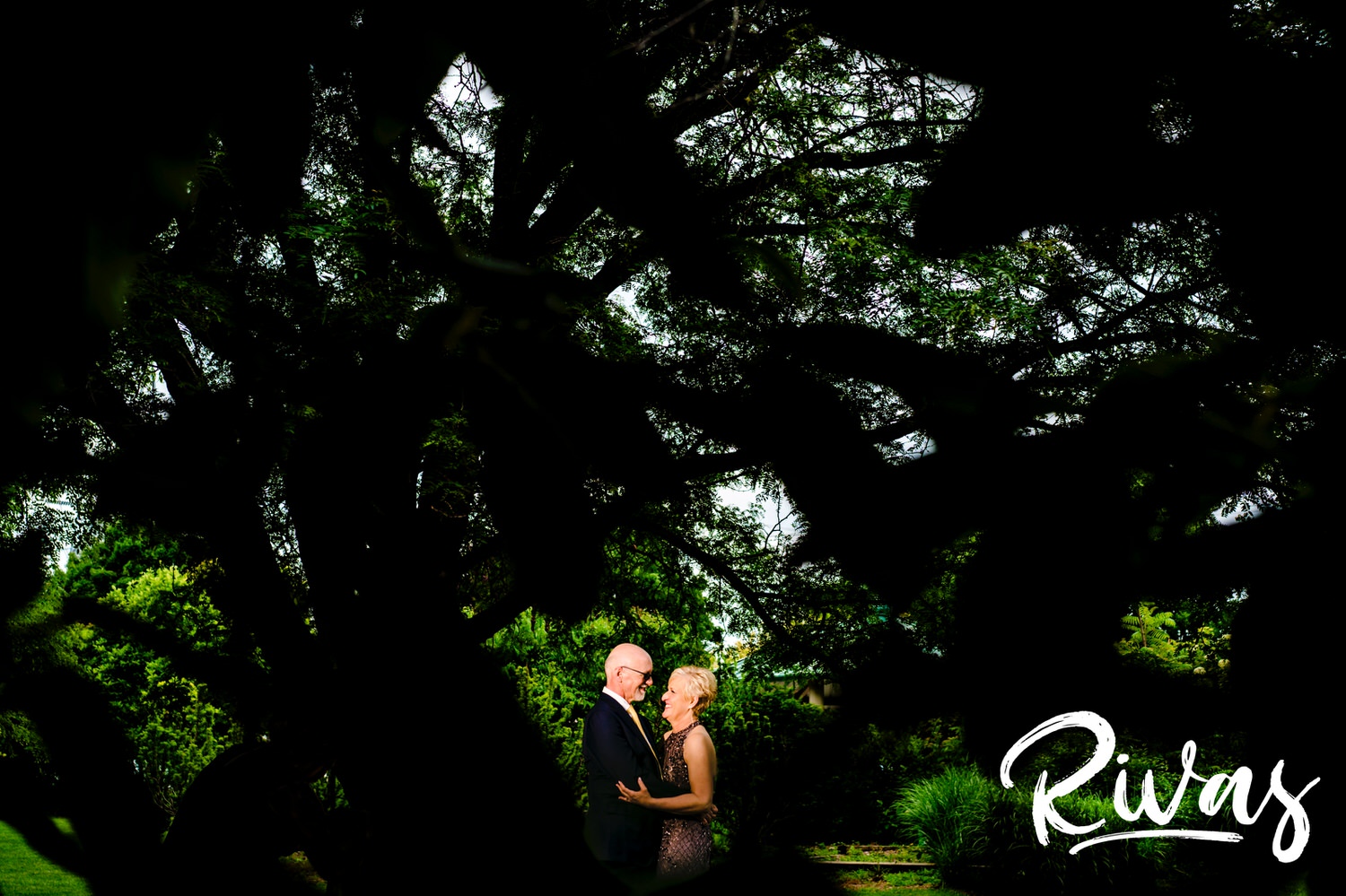 A colorful picture of a bride and groom sharing a kiss on a path at the Omaha OPPD Arboretum on the day of their wedding. 