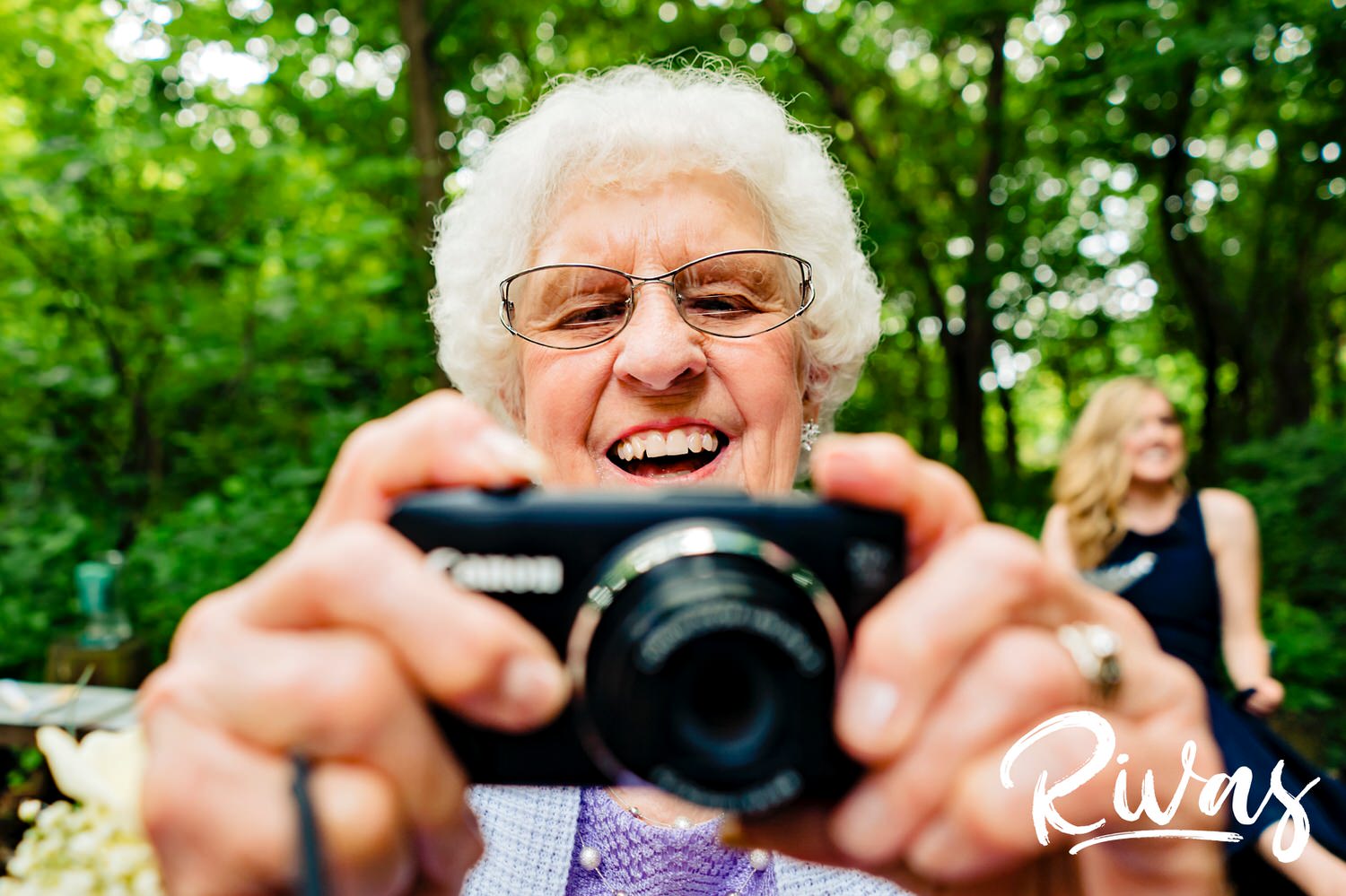 A candid picture of an older woman holding a camera out in front of her to take a photo. 