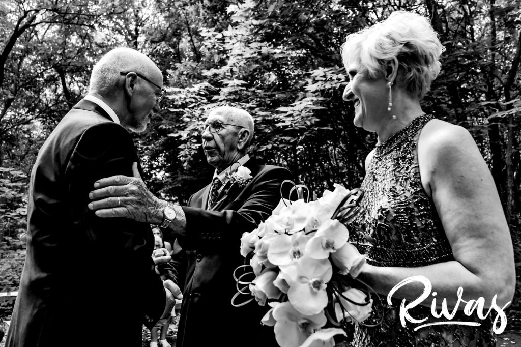 A candid, black and white picture of a bride's father giving her away to her husband during their outside wedding ceremony in Omaha. 
