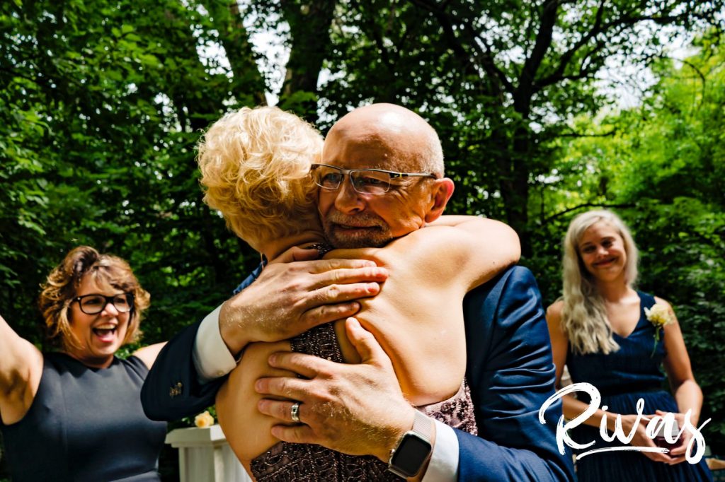 A colorful, candid picture of a groom hugging his new wife just after their intimate wedding ceremony at the Omaha Arboretum. 