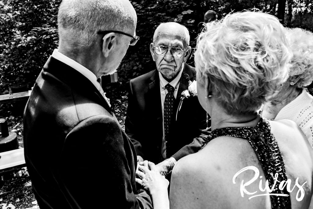 An emotional, black and white picture of a bride's father greeting his daughter and new husband after their wedding ceremony in Omaha. 