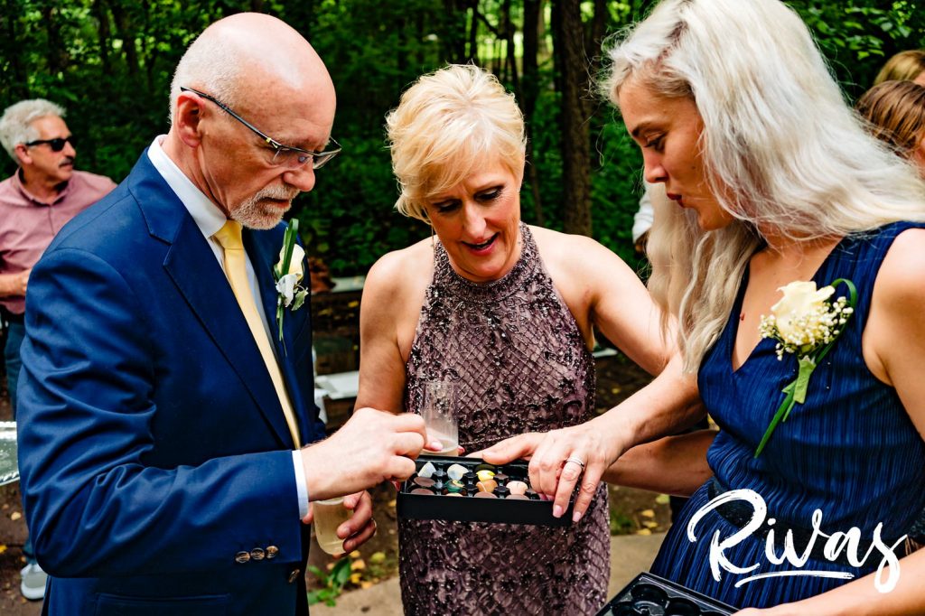 A candid picture of a bride and groom picking pieces of gourmet chocolate out of a box just after their wedding ceremony in Omaha. 