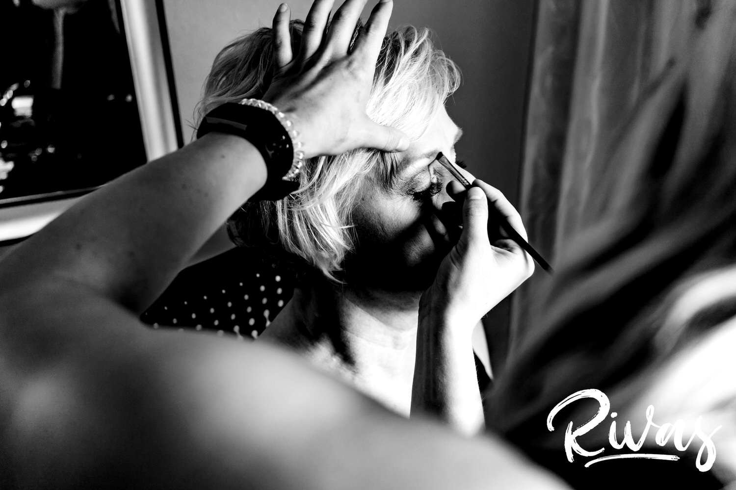 A candid black and white picture of a woman getting her make-up done on the morning of her Omaha, NE wedding. 